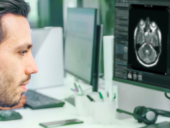 Radiologist looks at PET images and the head and neck cancer TNM-8 report, generated in mint Lesion™